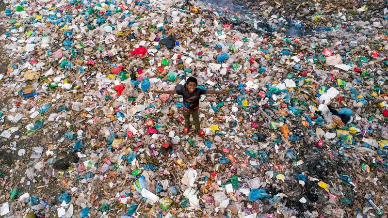 boy standing in field of plastic garbage