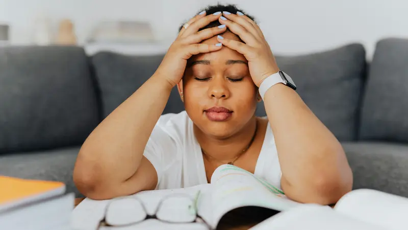 Woman holding her head, experiencing brain fog/fatigue after mental effort