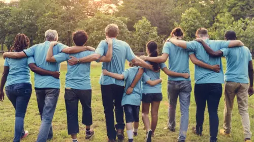 Group walking arm in arm towards sunset in woods