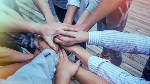Many hands reaching into center of group