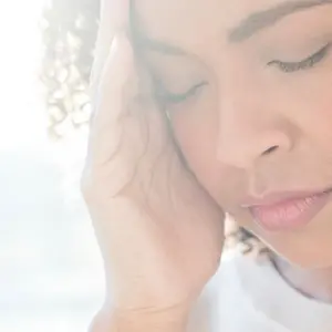 Woman with hands over her suffering with migraine