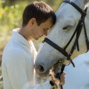 Man and horse heads together energy healing by the lake.