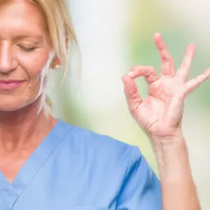Nurse smiling with eyes closed doing meditation gesture with fingers