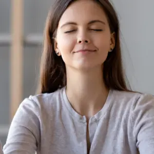 Calm young woman worker taking break doing yoga exercise at workplace