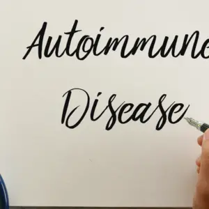 Top view of stethoscope, pen and hand writing ' Autoimmune Disease ' on notebook on wooden background