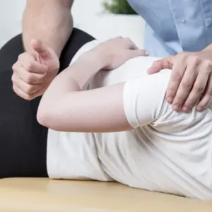 Physiotherapist is rehabilitating young woman back in medical office