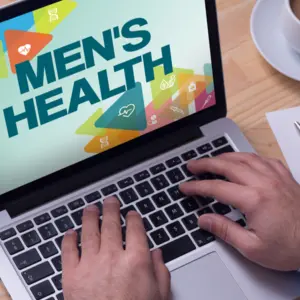 Doctor working on a laptop and MEN'S HEALTH on his screen
