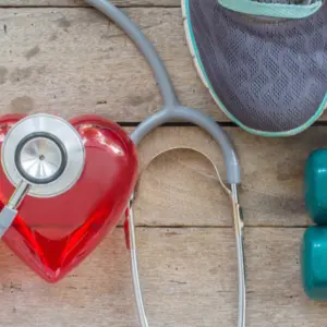 diet plan with sport shoes and bottle of water and Dumbell on wooden background