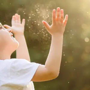 little girl catching soap bubbles in the summer