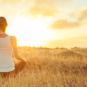 Woman meditating against a beautiful sunset.