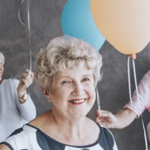 Happy senior people with colorful balloons celebrating their friend's birthday