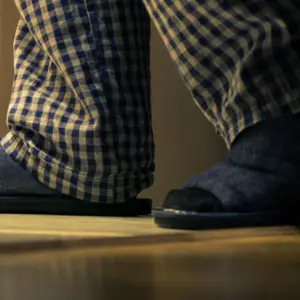 Adult man in pajamas walks to a bathroom at the night