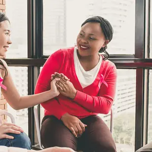 women wearing pink color clothes sitting in circle talking and meeting for breast cancer awareness campaign