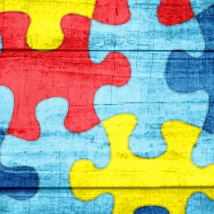 A colorful autism awareness puzzle background with wood texture illustration.