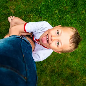 little boy with ADHD hangs on to his fathers leg being playful and full of energy, smiling and happy