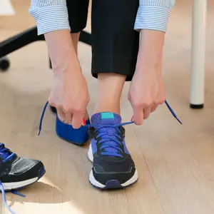 Woman changing high heels, office shoes after working day while sitting on the chair, ready to take a walk or run