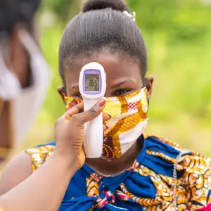 thermometer gun screen with the temperature digits-image of health official checking temperature during the covid-19 pandemic in Africa