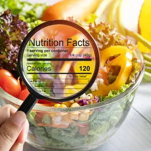 hand use the magnifying glass to zoom in to see the details of the nutrition facts from food , salad bowl