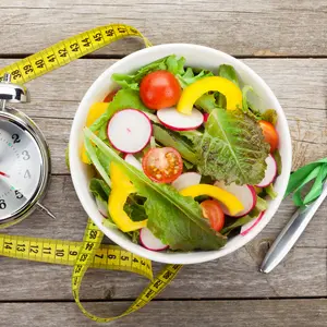 Fresh healthy salad and measuring tape on wooden table