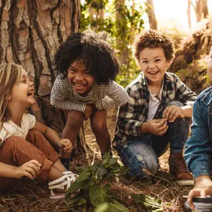 kids sitting together in forest and looking at camera