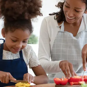 african american mother and tween daughter prepare vegan food