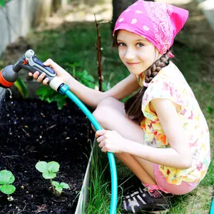 girl, watering the plants, from hose spray in the garden