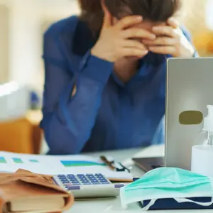 medical mask and hand disinfectant and stressed woman in background in temporary home office during the coronavirus epidemic