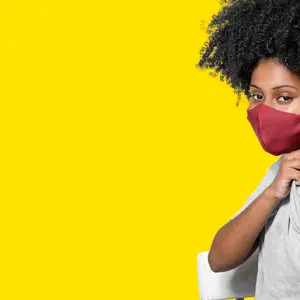 woman wearing protective mask shows the vaccine bandage, isolated on yellow background