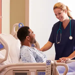 female nurse Talking To Male Patient In Hospital Bed