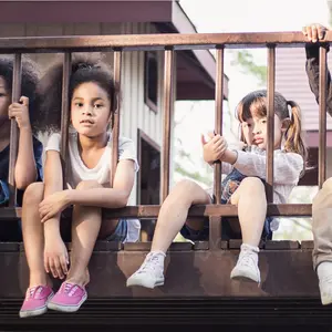 little children sitting behind the fence.