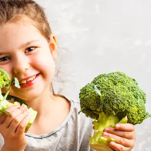 Little girl eating broccoli