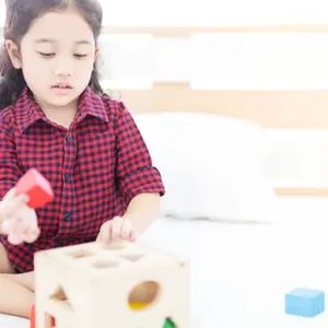  girl playing a wood puzzle toy on her bed, education training, children development toy