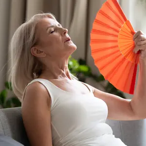 woman using waving fan suffering from hot flash