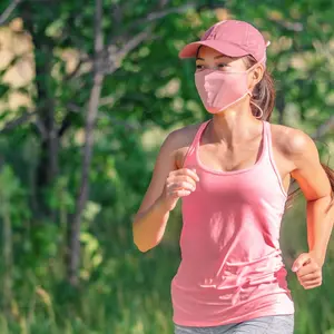 woman running outside with face covering while exercising jogging on run sport workout in summer