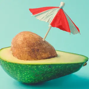 Tropical beach concept made of avocado fruit and sun umbrella.