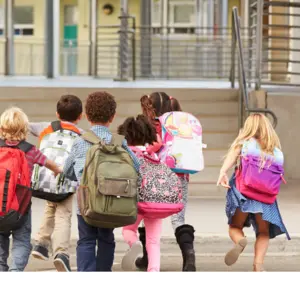 Elementary school kids running into school with large backpacks 