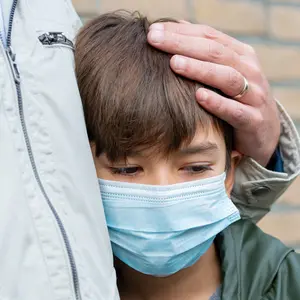 A father comforting a son in a medical mask, depression, being sad and lonely because of Covid-19