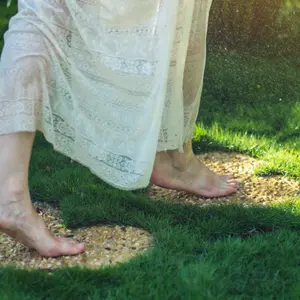 Girl walking barefoot on the stones in heart shape on green grass Girl walking barefoot on the stones in heart shape on green grass