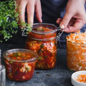 Fermented preserved vegetables food concept. Cabbage kimchi and sauerkraut sour cabbage glass jars, over rustic blue table