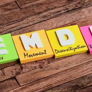 Colorful square papers with wooden white letters for the English acronym word, EMDR