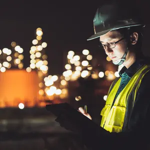 Asian man engineer using digital tablet working late night shift at petroleum oil refinery