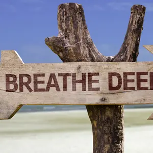 Breathe Deeply wooden sign with a beach on background