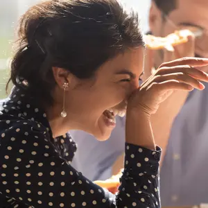 Laughing indian businesswoman in friends company eating pizza enjoy lunch together with colleagues