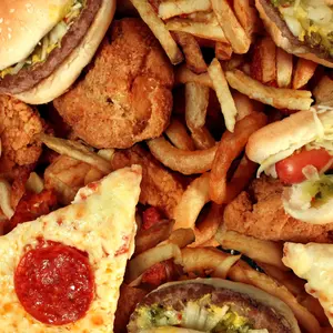 Fast food concept with greasy fried restaurant take out as onion rings burger and hot dogs with fried chicken french fries and pizza as a symbol of diet temptation resulting in unhealthy nutrition