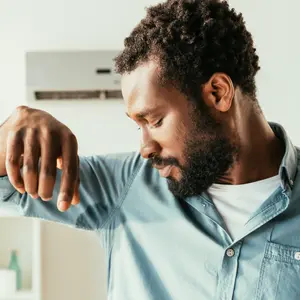 African American man looking at sweaty shirt 