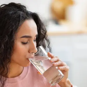 Woman Drinking Water From Glass In Kitchen