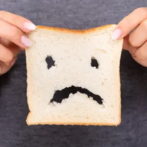Mid-section Of A Woman Hands Holding Sliced Bread With Unhappy Face Cut Out