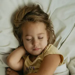 Portrait of cute little girl sleeping in bed with toy bear.