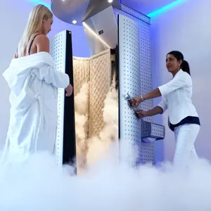 Female taking cryotherapy treatment with beautician standing at the capsule door.