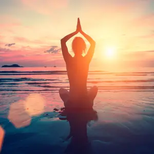 Silhouette young woman practicing yoga on the beach at sunset. Meditation.